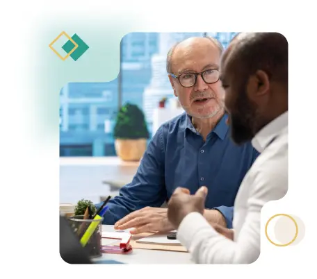 Two executives in conversation during a peer group meeting in a modern office setting