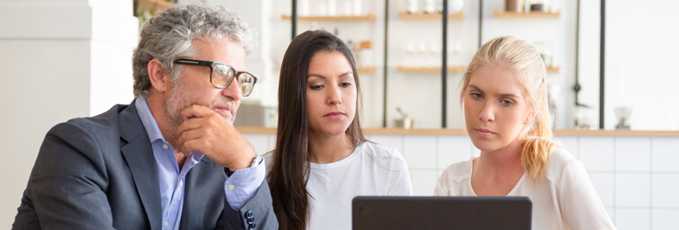 Image showing three people across different generations, seated in front of a laptop and looking at it with interest.