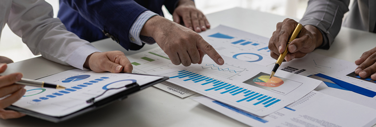 three people seen discussing by looking through few stats placed on a table