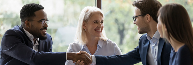 we can see four people at a discuttion at a office space, in which two colleagues are shaking there hands