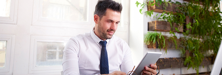 a person seen sitting on a sofa and using an ipad