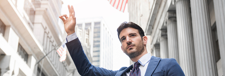 A person in a gray suit is seen raising their right hand upright.