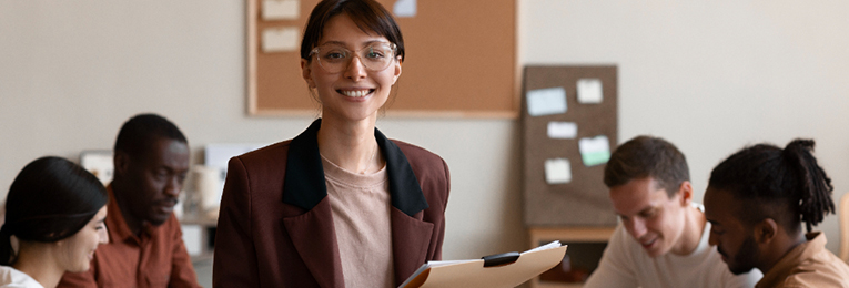 a women leader seen posing for a photo with a bright smile on her face in a office meeting
