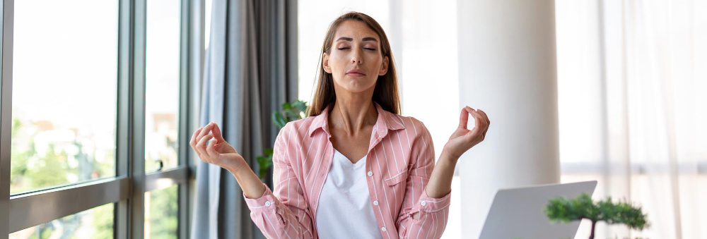 A woman is seen meditating with her hands facing upward in a tranquil and relaxed position.