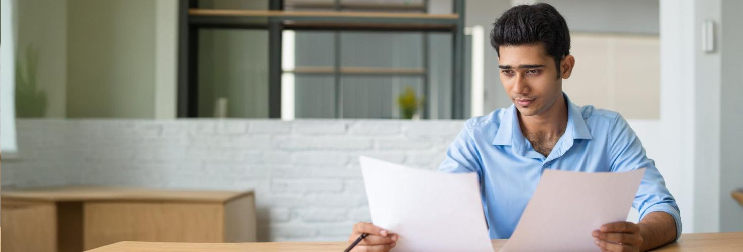 An image of a person holding and comparing two documents side by side.