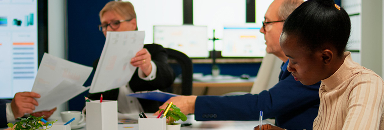 Four people reviewing documents and having a discussion in an office setting.